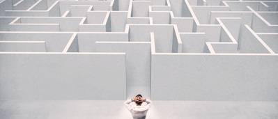 Ein Mann steht vor dem Eingang eines riesigen Labyrinths, er macht einen verzweifelten Eindruck
